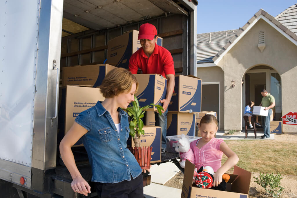 Family and worker unloading truck of cardboard boxes