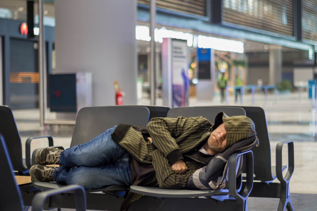Young man sleeping while waiting the plane at airport passenger terminal