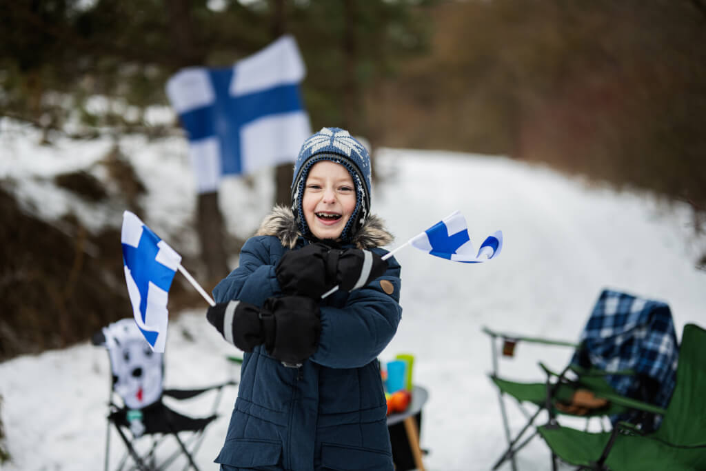 Gözəl bir qış günündə Finlandiya bayraqları olan fin oğlan.