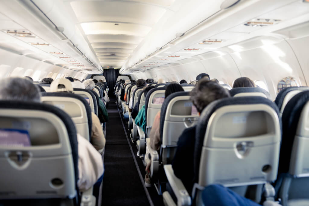 Interior of an airplane cabin with rows of seats down the aisle