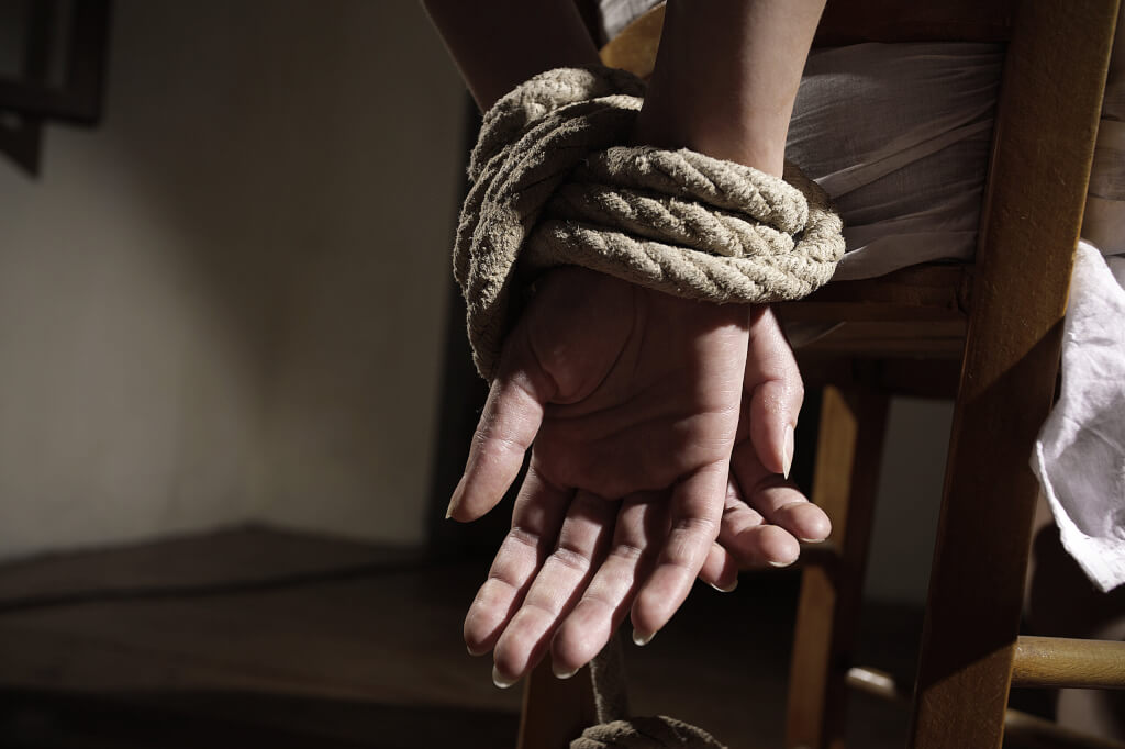 Young woman tied to a chair in a empty room, hands close up