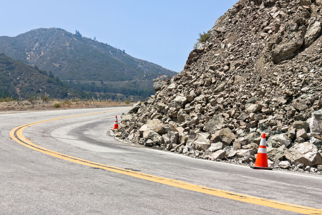 Two safety cones are used for the rock slide on the road.