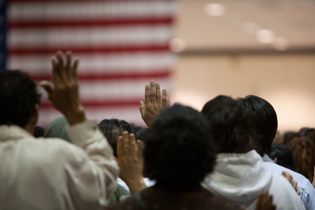 Immigrants of many ethnic backgrounds appear at a swearing in ceremony for US citizenship.
